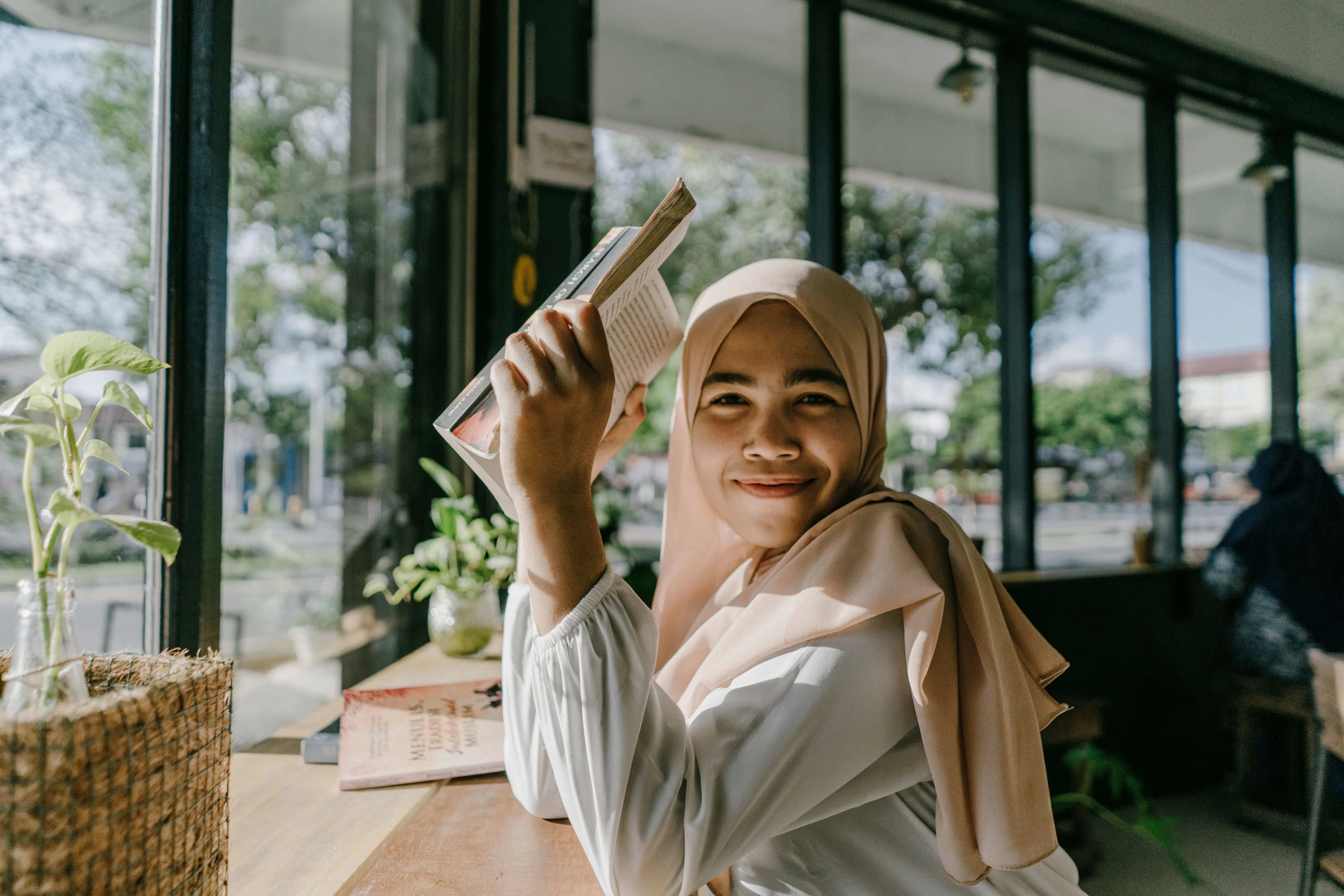 ilustrasi anak muda Indonesia sedang membaca buku fisik di kafe