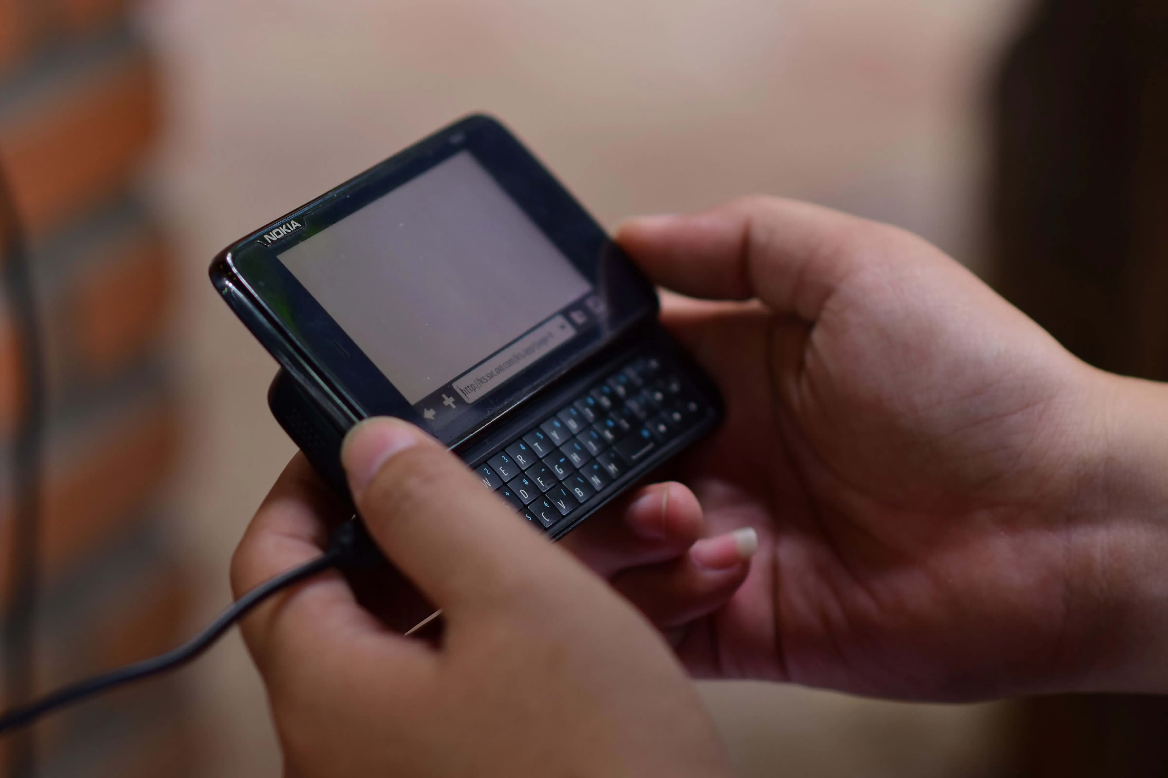 ilustrasi seseorang memegang sebuah dumbphone Nokia