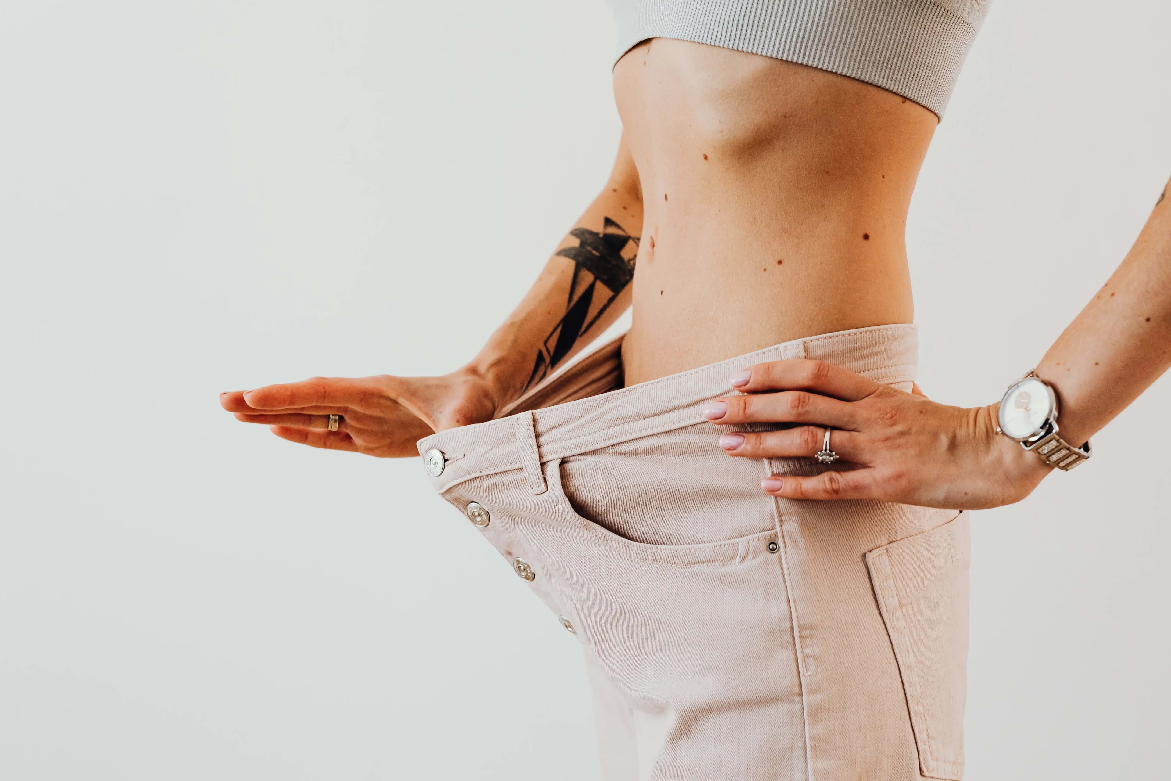 ilustrasi seorang wanita dengan celana longgar yang menunjukkan kemajuan penurunan berat badan
